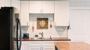 A modern kitchen with white cabinets, a black refrigerator, a wooden countertop, and a backsplash with a compass design. - Downstairs Studio style apartment on the River (Mermentau)