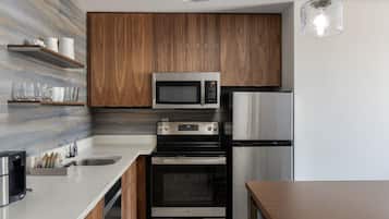 A modern kitchen with wooden cabinets, stainless steel appliances, and a marble backsplash.