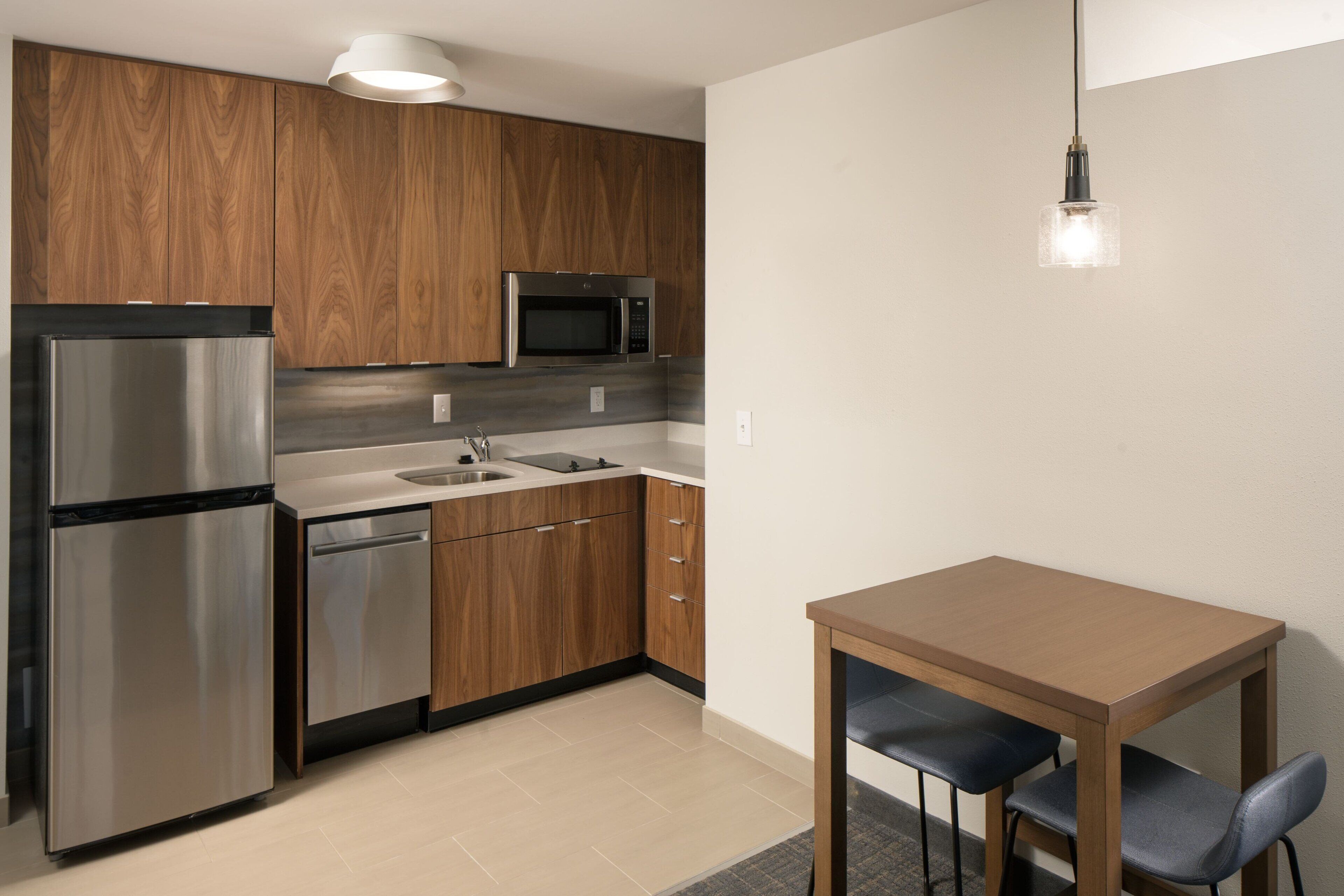 A modern kitchen with wooden cabinets, stainless steel appliances, and a wooden dining table with chairs.