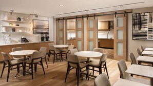 Une cuisine moderne avec des meubles blancs, un îlot central et un coin repas doté de tables et de chaises rondes.