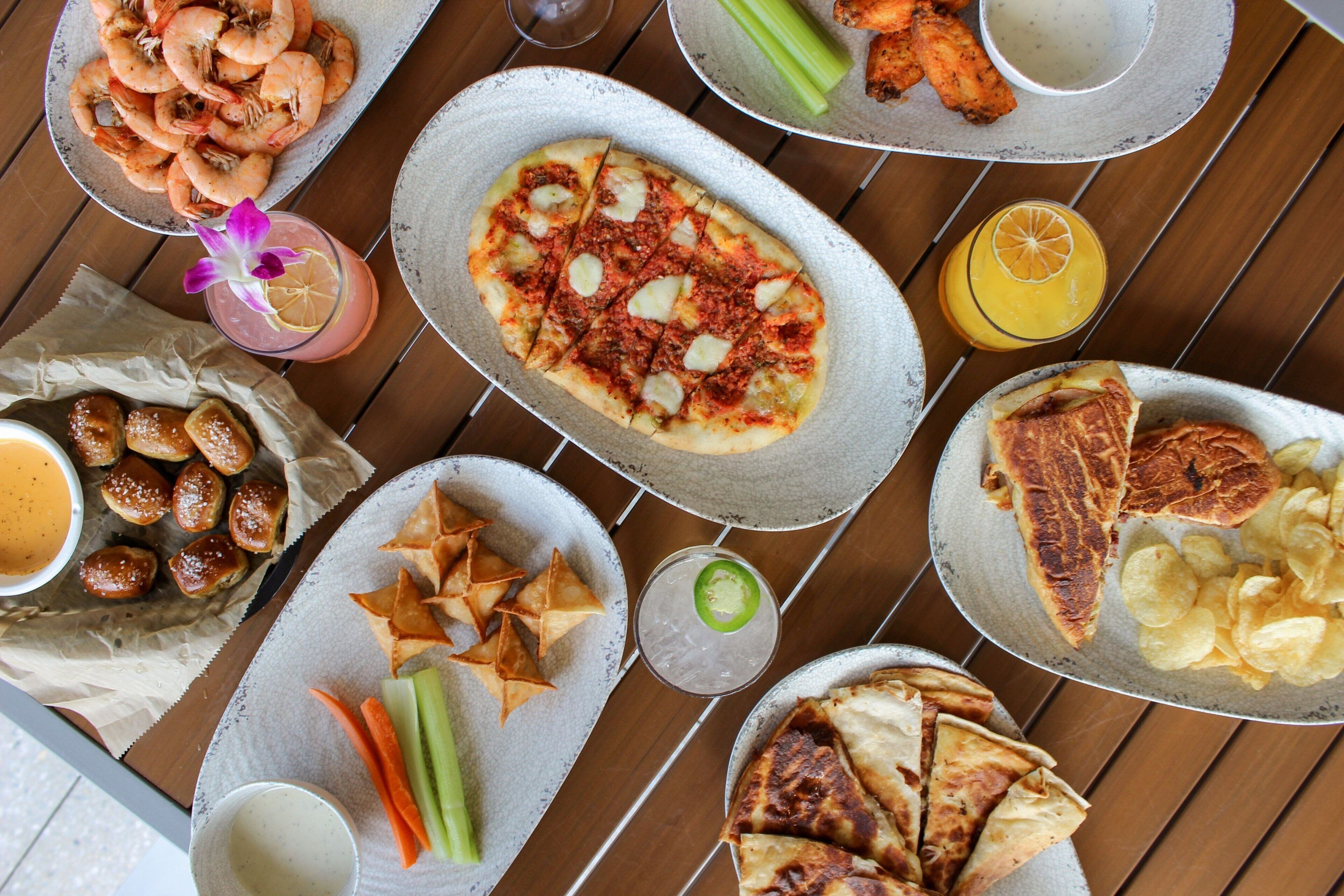 A table with various food items including shrimp, pizza, wings, and chips.