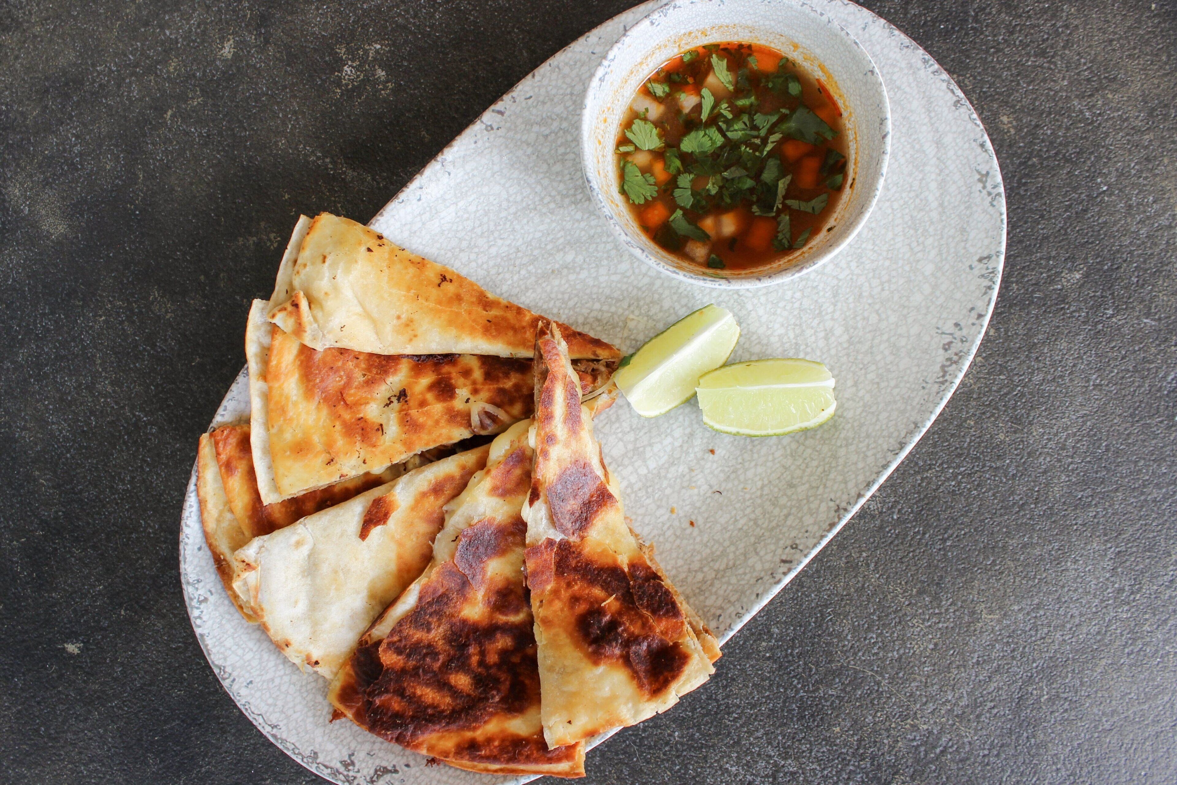 Un plato de quesadillas y un tazón de salsa.