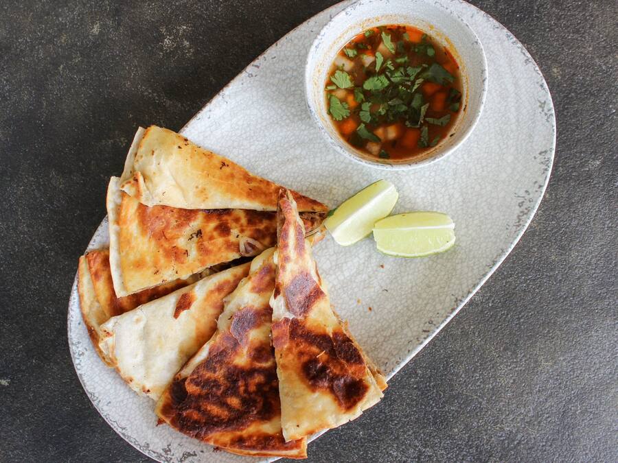 Un plato de quesadillas y un tazón de salsa.
