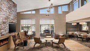 A spacious living area with a fireplace, comfortable seating, and large windows offering views. - Residence Inn by Marriott Tampa Wesley Chapel (Wesley Chapel)