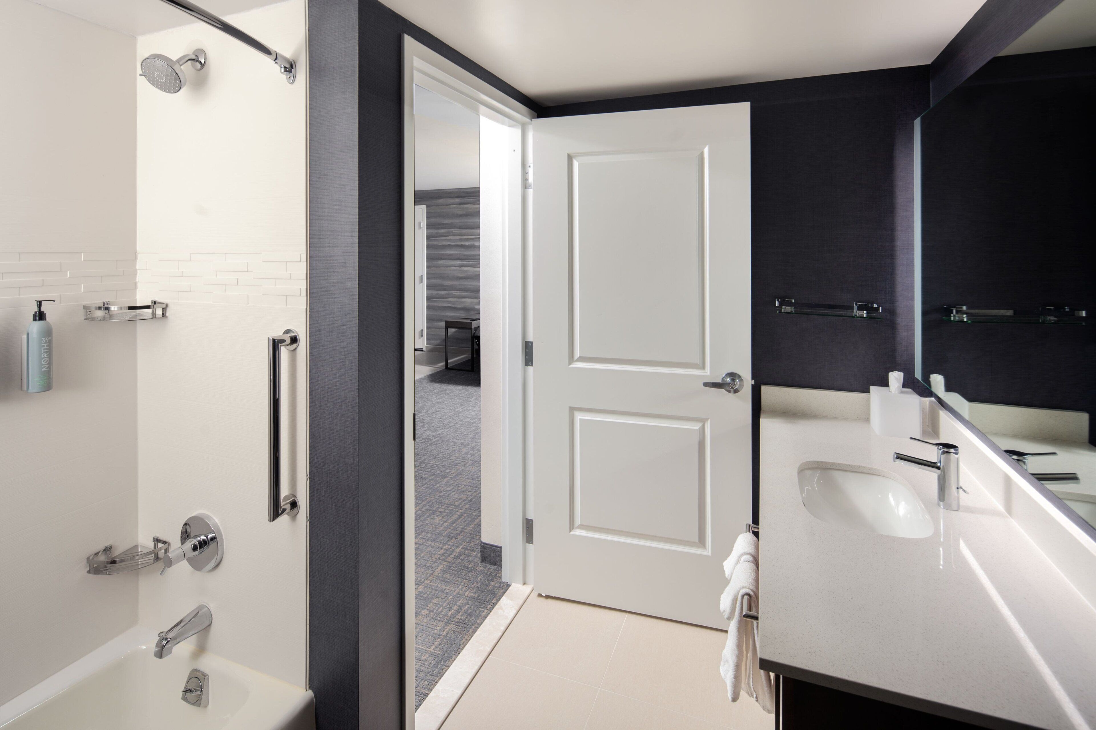 Un bagno moderno con una vasca, una doccia e un mobile lavabo con specchio.