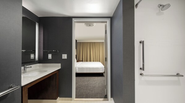 Un baño moderno con un espejo grande, un lavabo blanco y una zona de ducha.