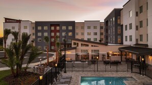 A hotel with a pool, outdoor seating, and a view of the sunset. - Residence Inn by Marriott Tampa Wesley Chapel (Wesley Chapel)