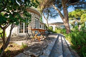 Un edificio de piedra con un ventanal circular y una mesa y sillas de madera afuera.