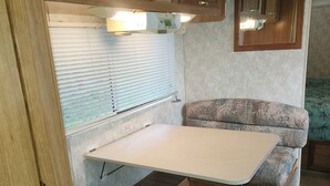 A compact RV interior with a kitchenette, a dining area, and a seating space. - Private Lake Superior Beachfront Retreat on 200 Acres (South Range)