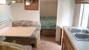 A compact RV kitchen with a dining area, a built-in stove, and a small sink. - Private Lake Superior Beachfront Retreat on 200 Acres (South Range)