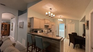 A spacious kitchen with a central island, bar stools, and a dining area with a table and chairs.