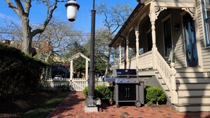 A brick pathway, a white picket fence, a street lamp, and a barbecue grill. - Beautifully Renovated in Heart of Cape May - 1 Block to Beach; 1 Block to Mall (Cape May)