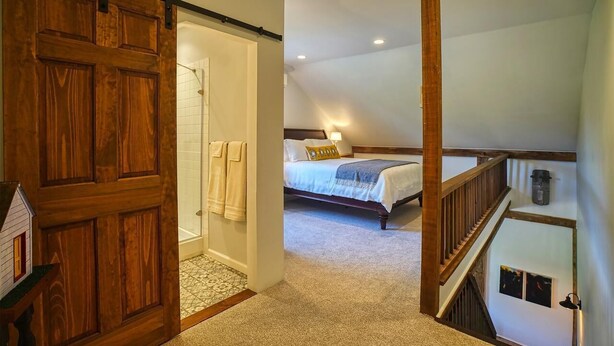 A bedroom with a bed, a wooden door, and a staircase. - Historic charm, all new amenities at Swallow's Rest: West (West Grove)