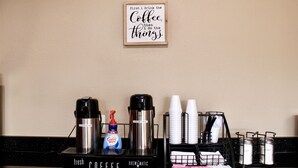 A coffee station with a coffee maker, a bottle of coffee creamer, and a coffee grinder. - HomeTown Inn & Suites (Longview)