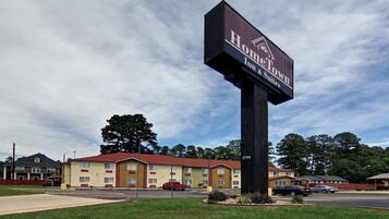 A hotel sign with 'HomeTown Inn & Suites' branding, a parking lot, and a building with a red roof.