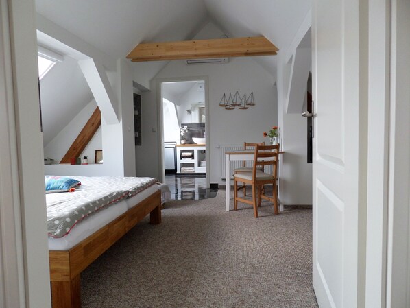 A bedroom with a bed, a wooden chair, a desk, and a radiator.
