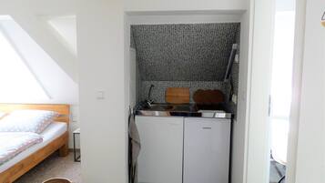 A compact kitchen with a sink, wooden cutting board, and a refrigerator.