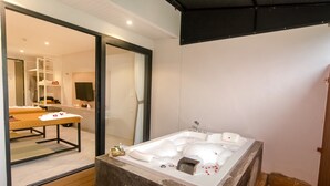 Um banheiro moderno com uma banheira grande, piso de madeira e um espelho refletindo o ambiente.