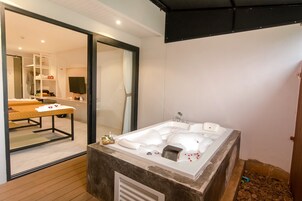 Un baño moderno con una bañera grande, piso de madera y un espejo que refleja el cuarto.