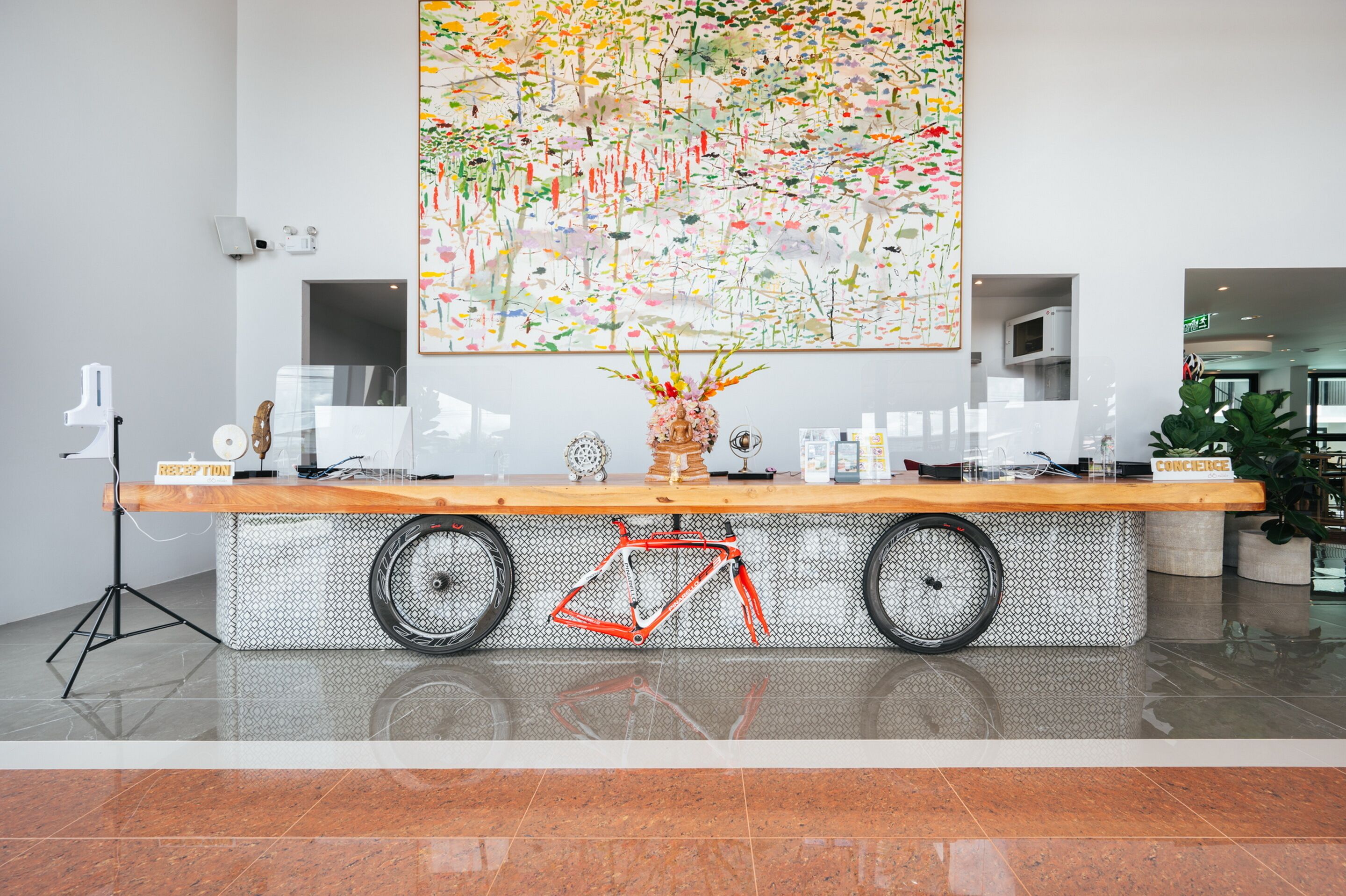 Un mostrador de recepción con una bicicleta, una obra de arte floral grande y un cartel que indica 'CORCERS'.