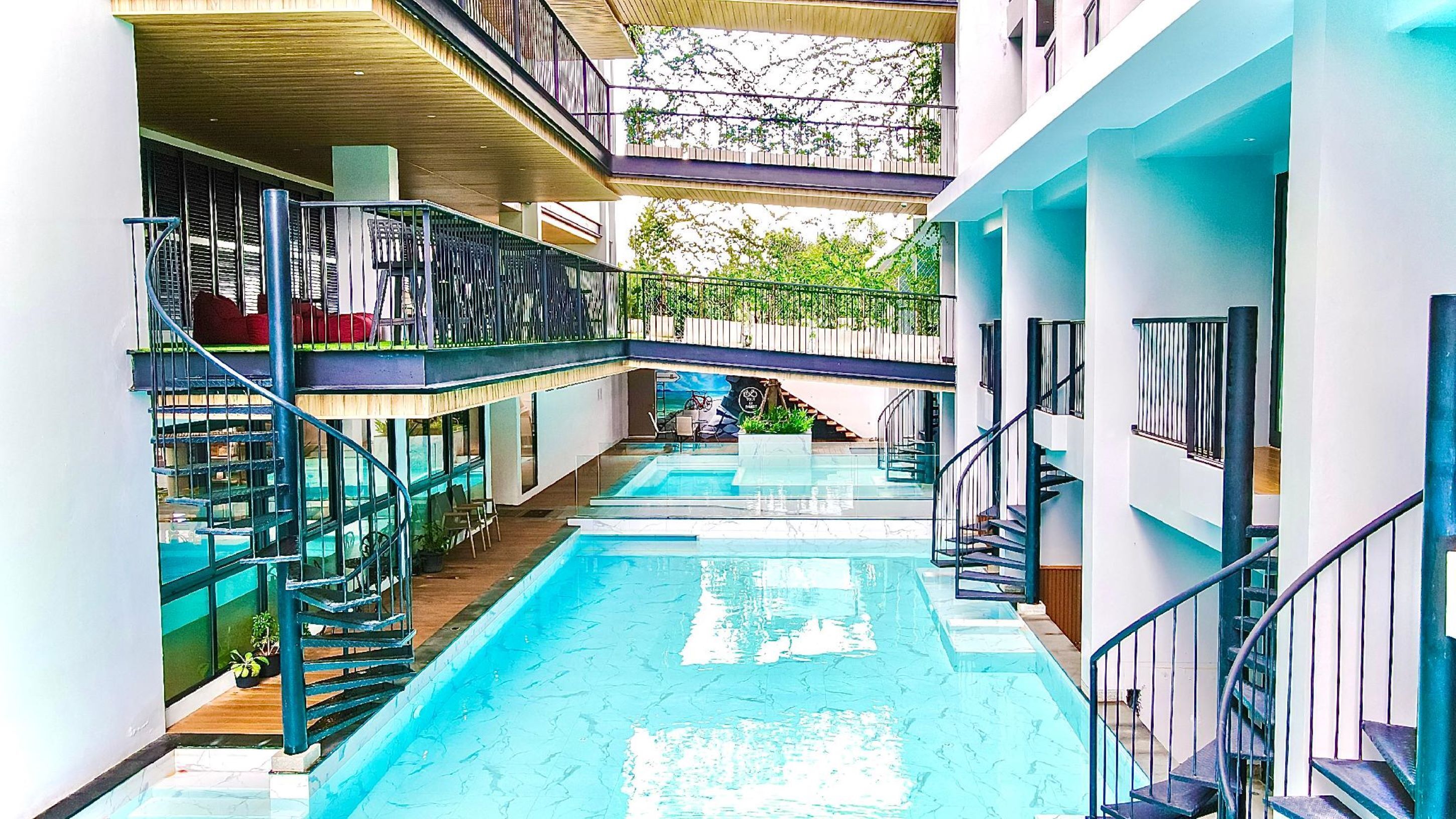 A multi-level indoor swimming pool with glass railings and a staircase on the right.