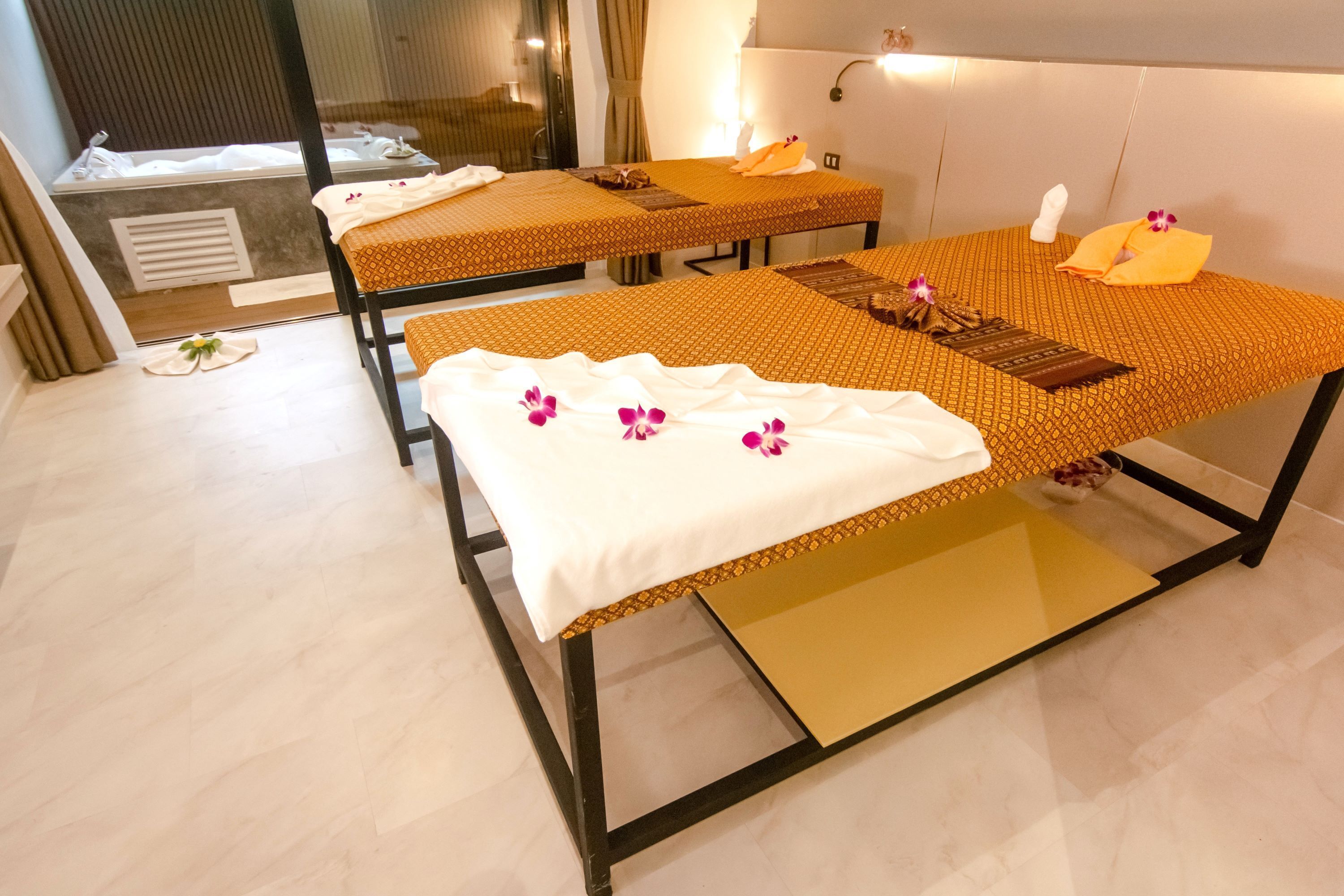 Un cuarto de spa con dos camillas de masaje, cada una con una toalla y un arreglo floral.