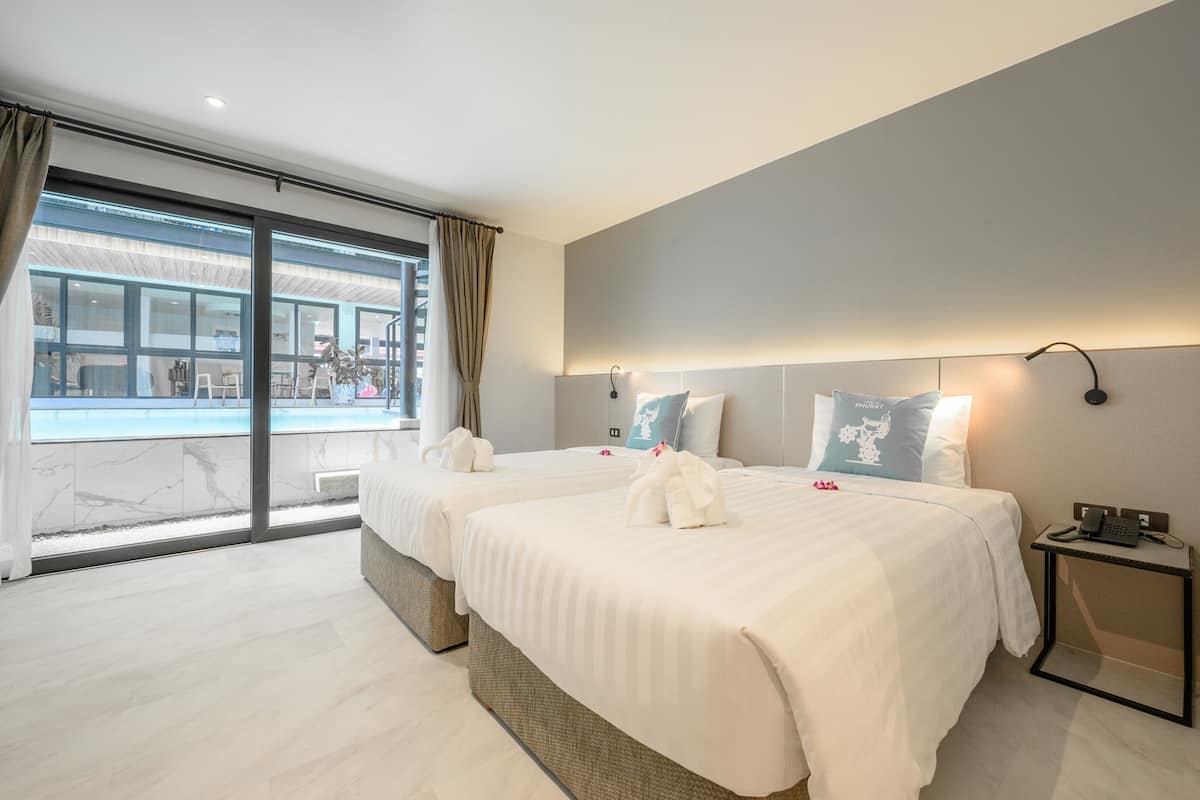 A hotel room with two beds, a view of a pool, and a small bedside table with a phone.