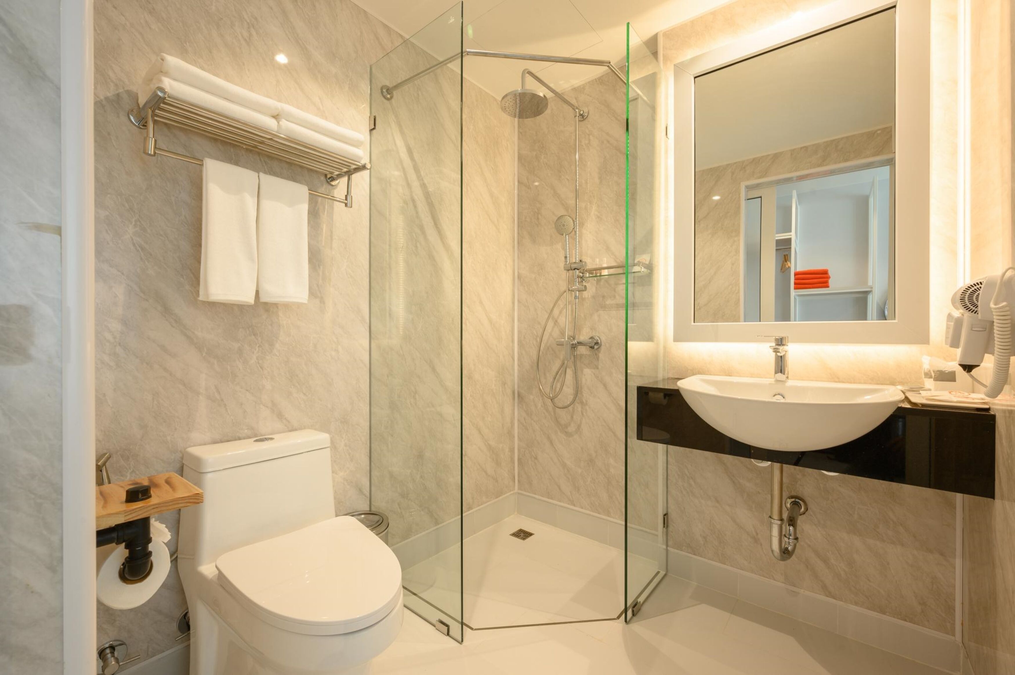 Une salle de bain moderne avec une douche à parois de verre, des toilettes blanches et un meuble-lavabo avec un évier et un miroir.
