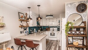Una cocina moderna con una isla central, iluminación colgante y un reloj en la pared.