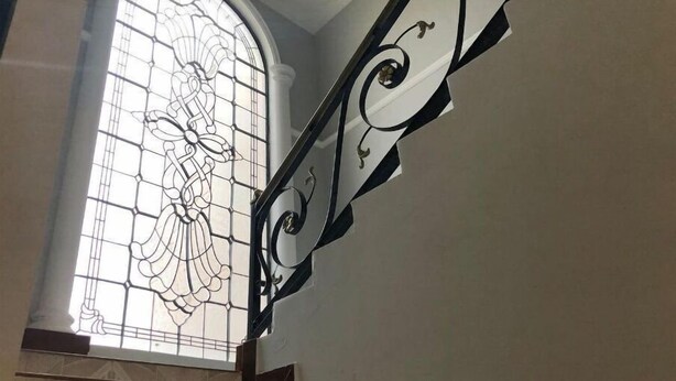 A staircase with a stained glass window featuring a floral design.