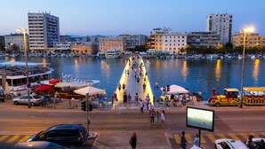 Un passeig marítim amb vaixells, una zona per vianants i edificis al fons.
