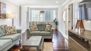 A modern living room with a grey sofa, a coffee table, and a TV on a wooden stand. - 1001 Walk to Soccer 2026, MBS, DT ATL, Parking (Atlanta)