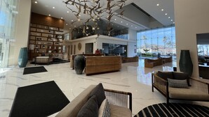 A spacious lobby with a high ceiling, modern furniture, and a large window offering a view of palm trees. - Increible depa con vista al mar. Z.dorada(factura) (Mazatlán)