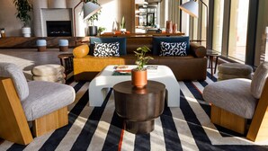 A modern living room with a fireplace, sofas, armchairs, and a coffee table. - Hotel Indy, Indianapolis, a Tribute Portfolio Hotel (Indianapolis)