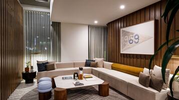 A modern living room with a sectional sofa, a coffee table, and a large framed artwork on the wall.