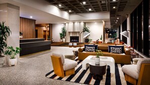 A modern lobby with a fireplace, seating area, and large windows. - Hotel Indy, Indianapolis, a Tribute Portfolio Hotel (Indianapolis)