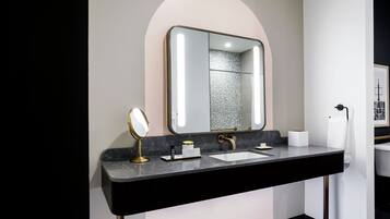 Un baño moderno con encimera negra, dos lavamanos, un espejo grande y un perchero para toallas.