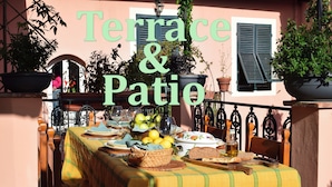 Eine Terrasse mit Esstisch, umgeben von Topfpflanzen und einem Geländer.