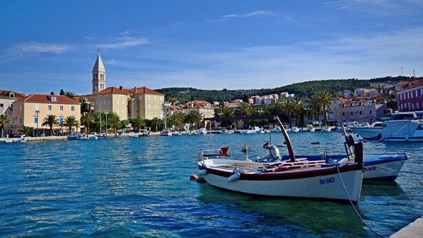 A marina with boats docked, a prominent church tower, and a coastal town with buildings and palm trees. - A2 - Cozy Apartment, Best Location in Supetar (Supetar)