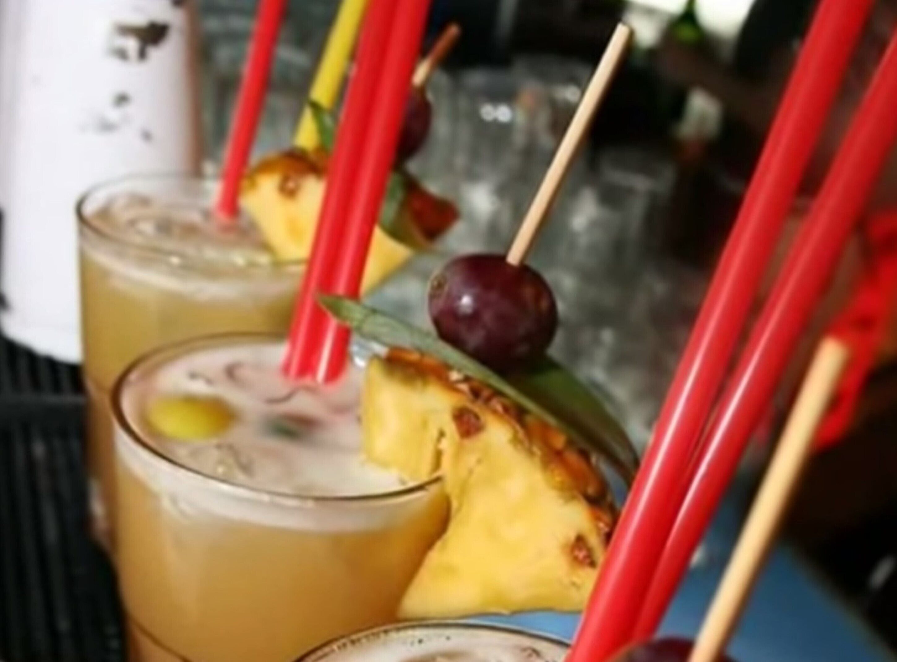 Un bar où les boissons sont décorées de tranches d’ananas et servies avec des pailles rouges.
