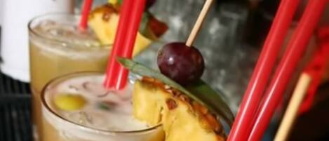 Un bar où les boissons sont décorées de tranches d’ananas et servies avec des pailles rouges.