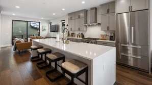 A modern kitchen with a large island, stainless steel appliances, and a dining area with bar stools.