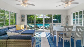 A sunlit room with a pool, white furniture, and ceiling fans. - Swim Up Bar - Outdoor Paradise! (Delray Beach)