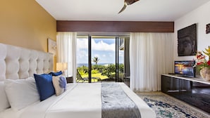 Ein Hotelzimmer mit einem großen Bett, einem Deckenventilator, Meerblick und einem Fernseher auf einer Konsole.