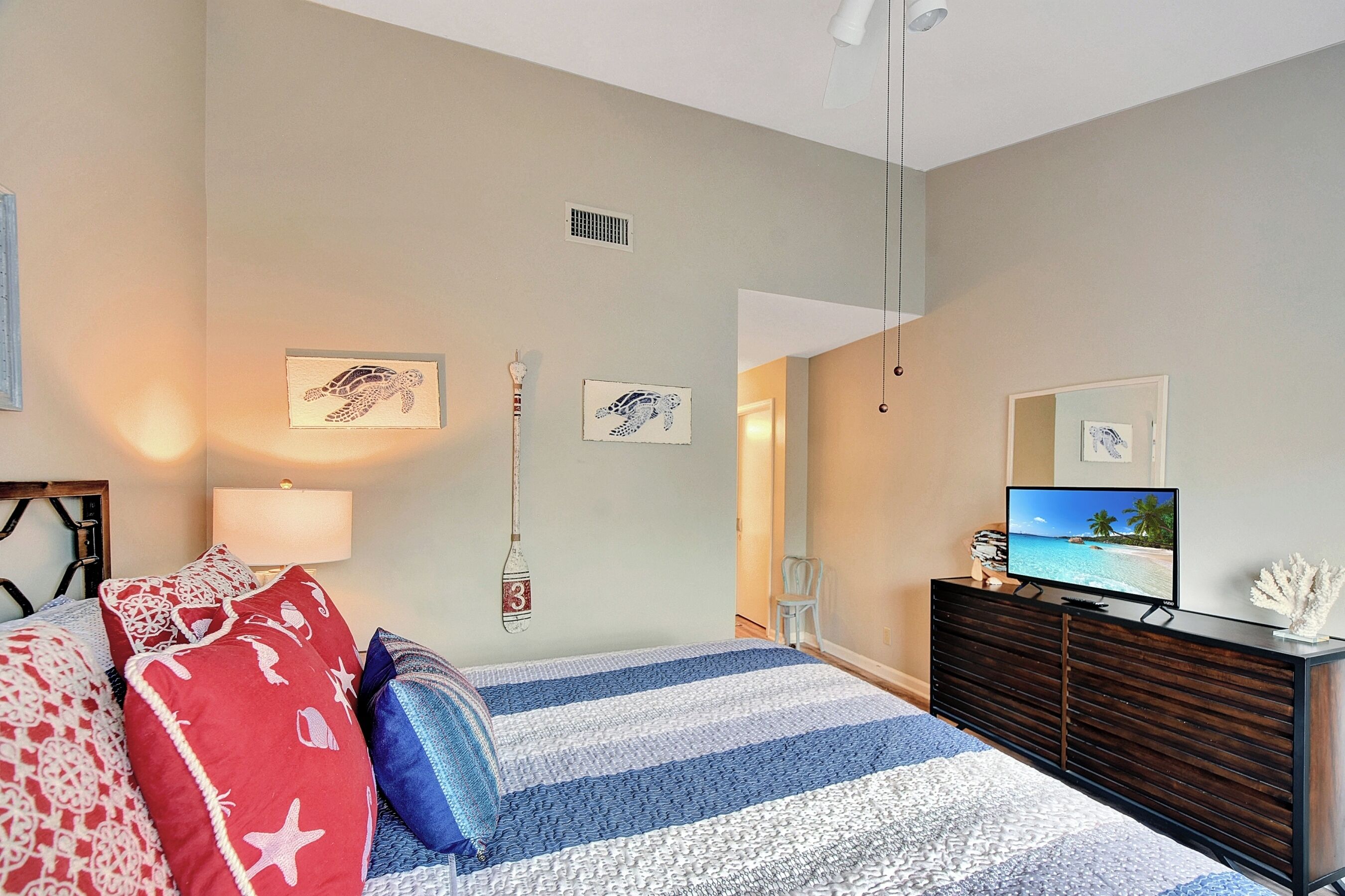 A bedroom with a bed, a dresser, a television, and wall art.