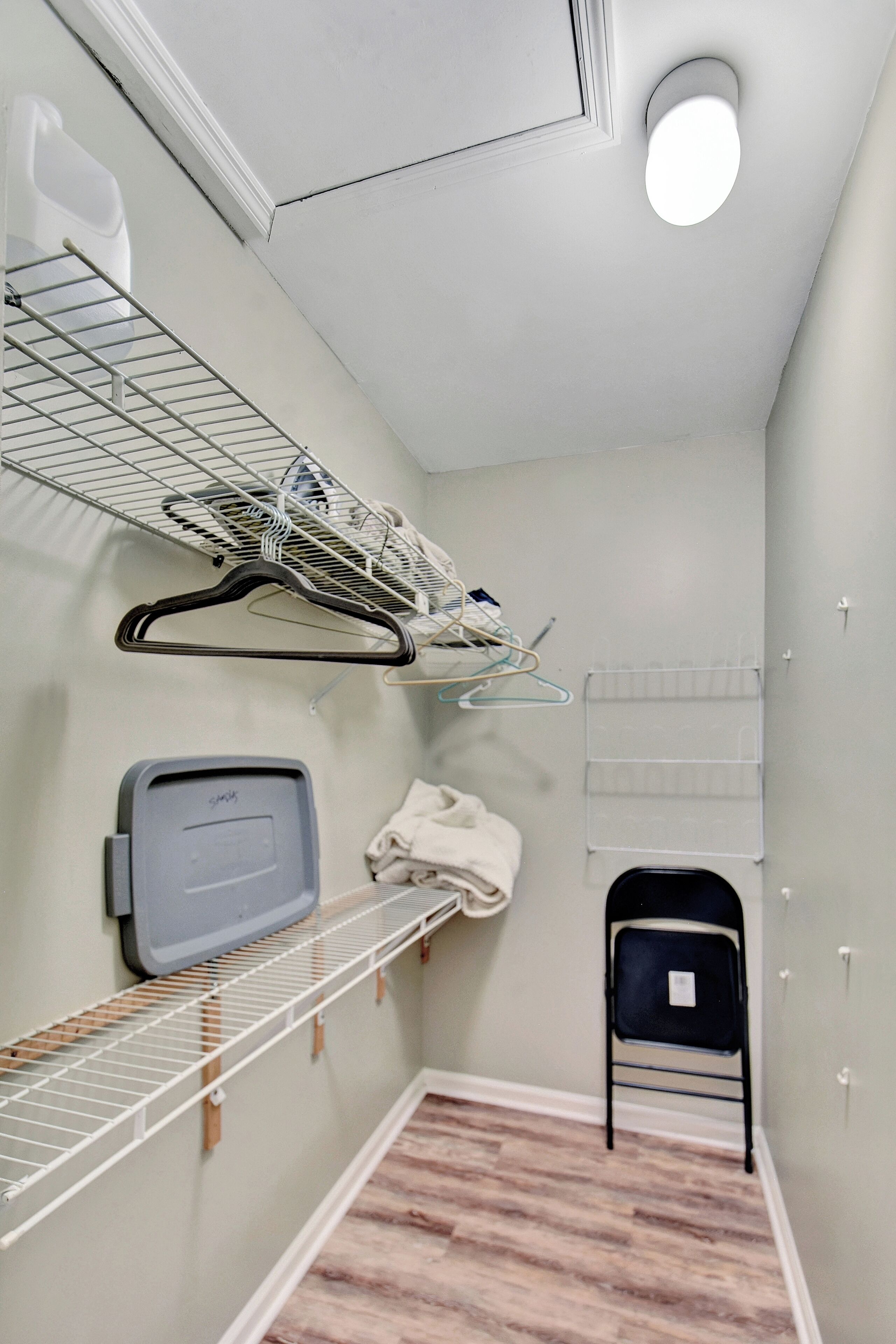 A laundry room with a drying rack, a folding station, and a chair.