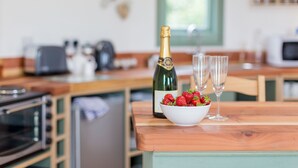 Una cocina con encimera de madera, una botella de champán, dos copas y un bol de fresas.