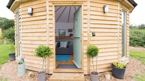 Una cabaña de madera con una pequeña cocina, un sofá y dos plantas en macetas.