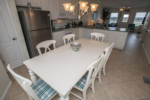 A kitchen with white cabinetry, a stainless steel refrigerator, a dining table with four chairs, and a chandelier. - Sea Cliffs rental with elevator SUN-SUN Rental (Port Saint Joe)