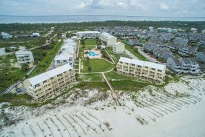 An aerial view of a coastal hotel with multiple buildings, a central pool, and a beach area.